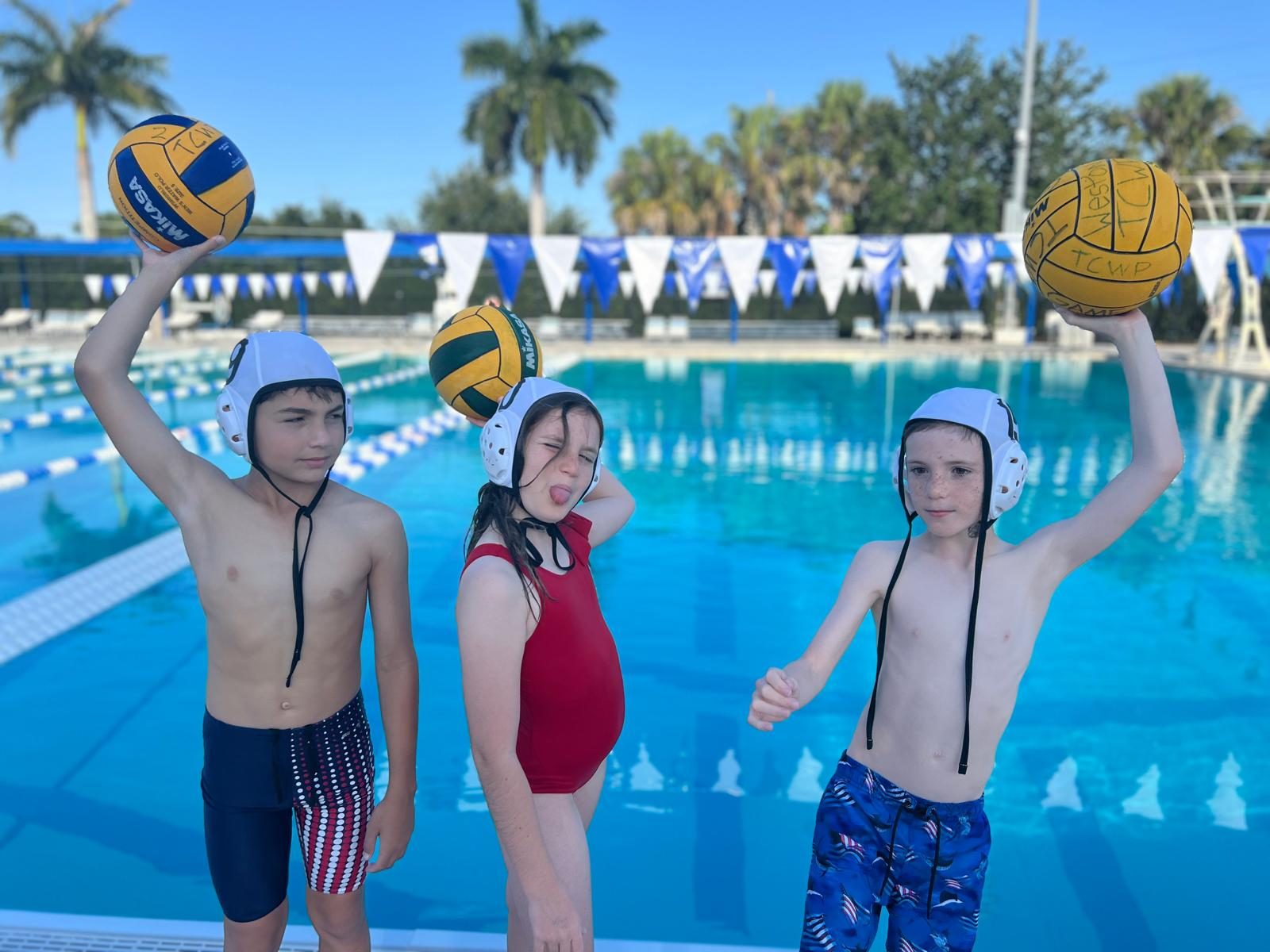 Youth water polo players poolside with balls