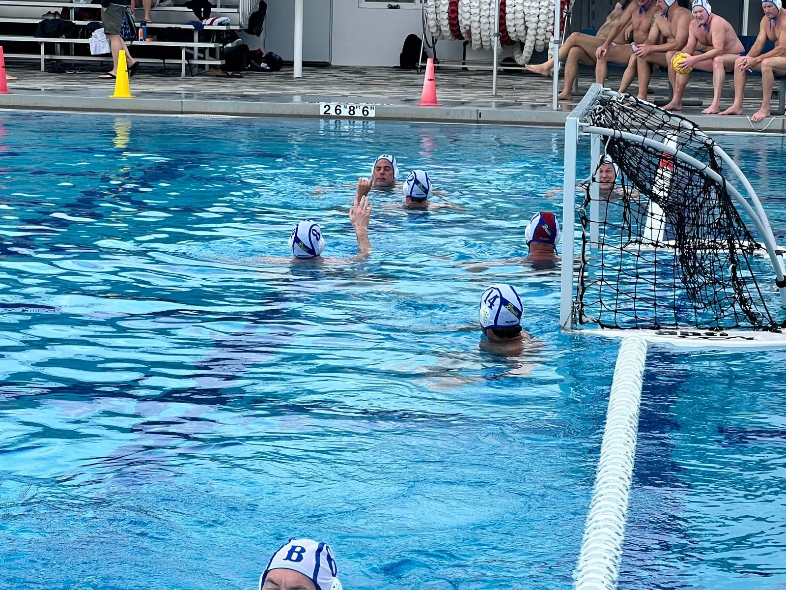 Masters water polo team huddled at the goal